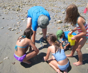 Four kids and one adult volunteer digging in sand